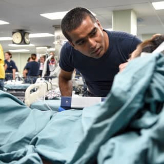 A corpsman caring for a patient at the bedside