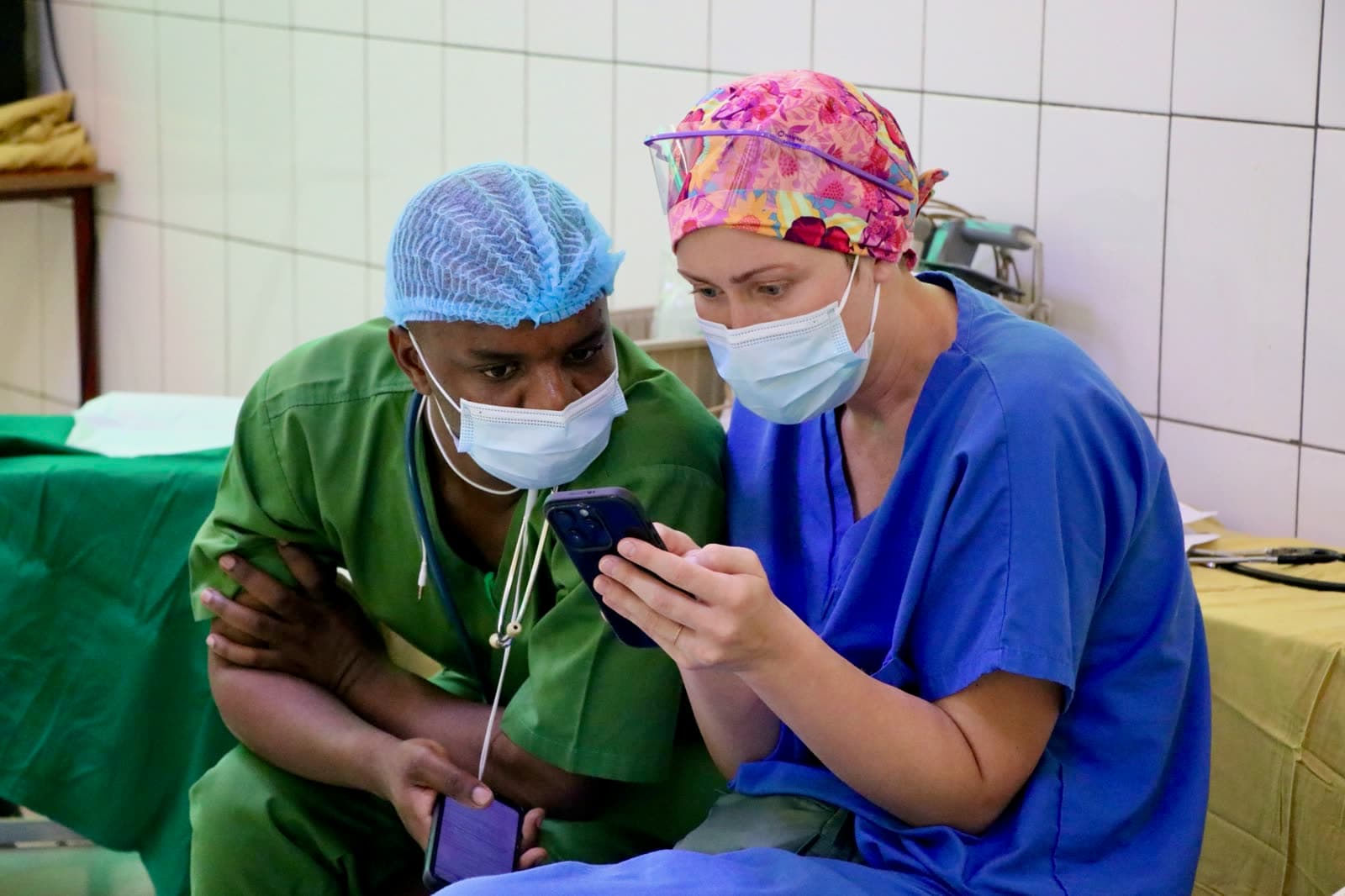Two clinicians in scrubs conferring over a patient chart